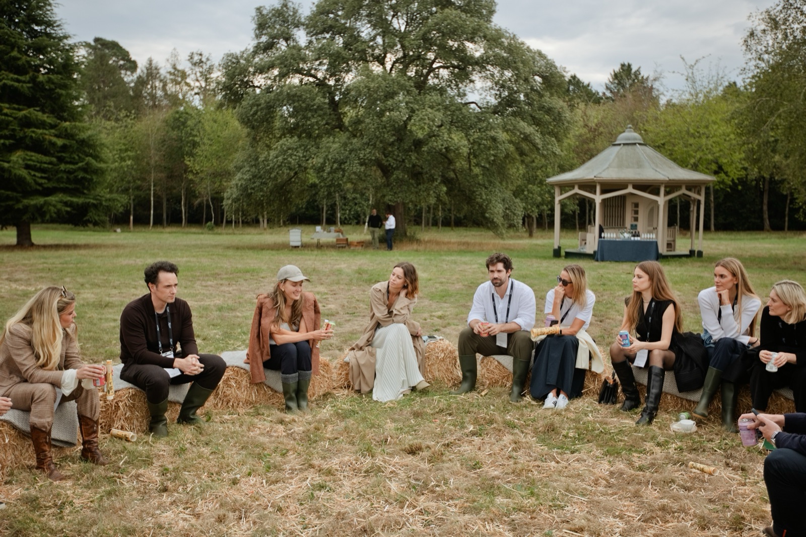Xenia Tchoumi with Sophia Amoruso, Áslaug Arna Sigurbjörnsdóttir, Matt Fitzpatrick, Wulfie Bain and fellow guests seated on hay bales on the main lawn of Hedsor House for the Hay Bale Conversations at The Hedsor Hundred