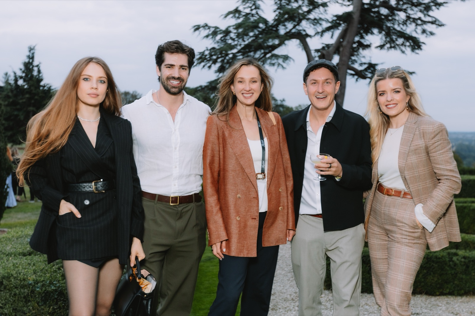 Xenia Tchoumi with Wulfie Bain and fellow guests in the gardens of Hedsor House at dusk, The Hedsor Hundred 2026